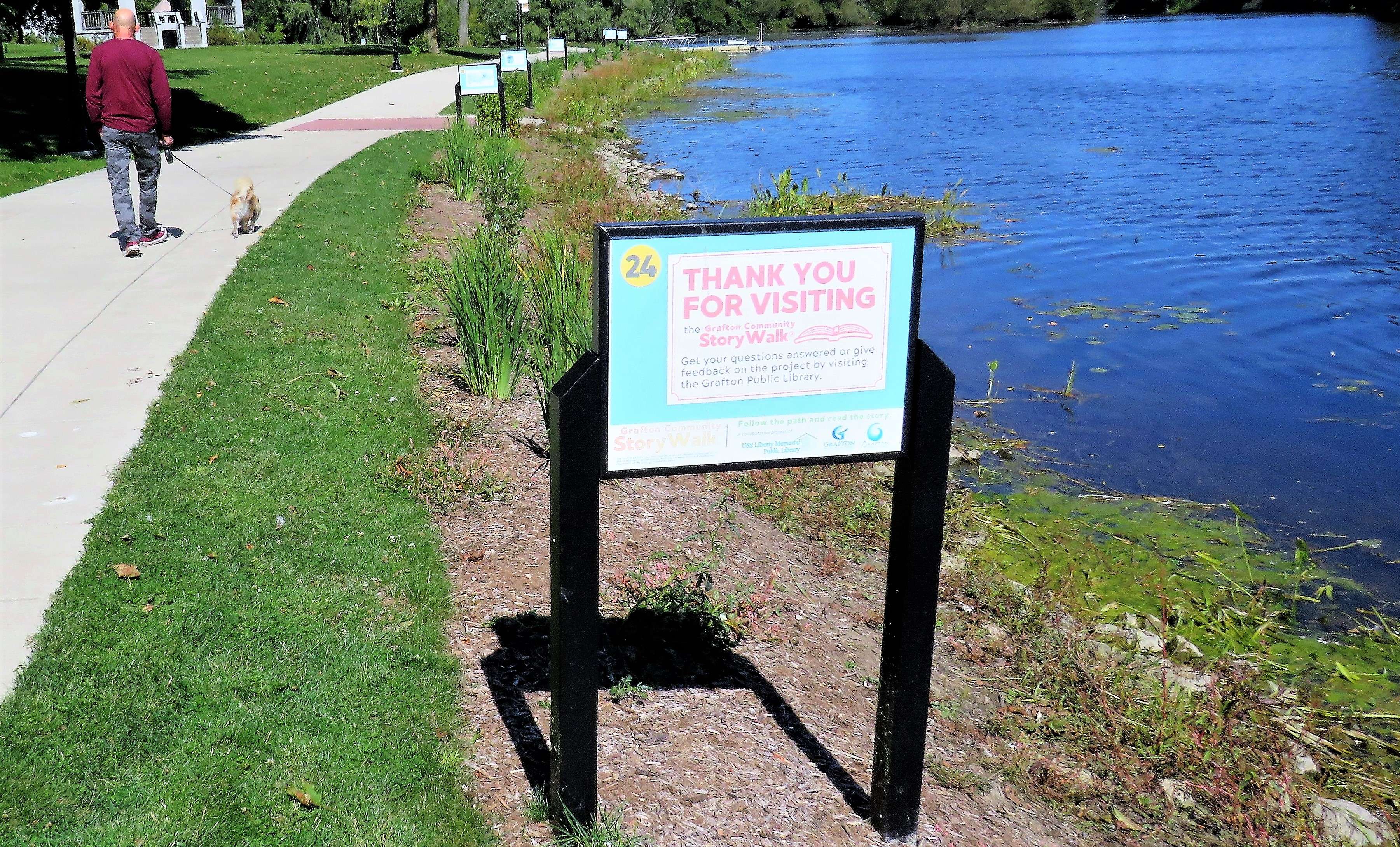 A sequence of StoryWalk panels along a riverside walking path